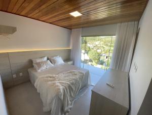 1 dormitorio con cama y ventana grande en Chalé lindo para toda família nas montanhas !!!, en Domingos Martins