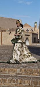 Una donna con un vestito in piedi davanti a un palazzo di Guest House Art Postindoz a Khiva