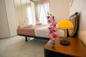 コンヴェルサーノにあるCasa Simoneのベッドルーム1室(ベッド1台、ランプと花付きのテーブル付)