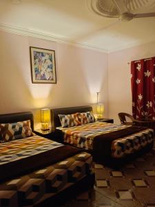 a hotel room with two beds and two lamps at Alfa Roomstay in Pantai Cenang