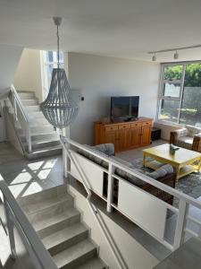 a living room with stairs and a tv and a table at Sunset Cove in Plettenberg Bay