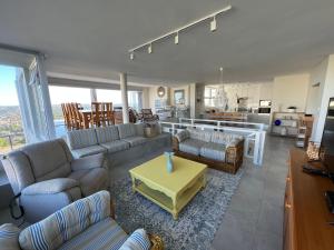 a living room with couches and a table and a kitchen at Sunset Cove in Plettenberg Bay