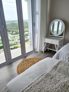 a bedroom with a bed and a chair and large windows at Sunset Cove in Plettenberg Bay