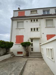 a white building with red shutters on it at L’Abri Cotier - Appartement face mer 2/4 personnes in Fort-Mahon-Plage