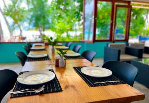 un lungo tavolo in legno con sedie e piatti di Si! Beach House a Dhiffushi