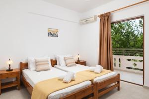 two beds in a room with a window at Aphrodite Apartments in Kalyves