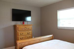 a bedroom with a bed and a dresser with a flat screen tv at Pool house in Port Charlotte in Port Charlotte