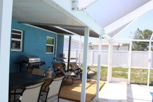 a patio with a white pergola and chairs at Pool house in Port Charlotte in Port Charlotte