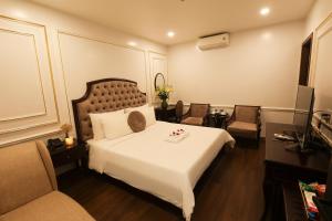 een hotelkamer met een groot bed en 2 stoelen bij Royal Văn Phú Hotel in Hanoi
