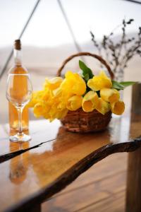 Glamping Park في Khndzorut: سلة من الزهور الصفراء بجوار زجاجة من النبيذ