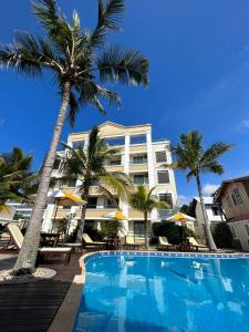 un hotel con piscina y palmeras en Golfinhos Apart Hotel, en Florianópolis