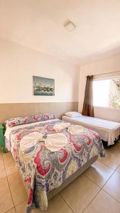 um quarto com uma cama com uma colcha colorida em Pousada Acquaville em Bertioga