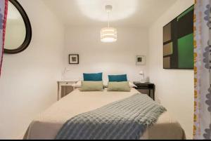 une chambre blanche avec un grand lit avec des oreillers bleus dans l'établissement CENTRAL MONKEY APARTMENT - Grupo RH Santander, à Santander