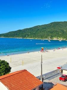 una playa con un grupo de personas en el agua en Golfinhos Apart Hotel, en Florianópolis
