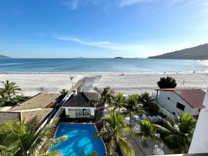 una vista aérea de una playa con palmeras y una casa en Golfinhos Apart Hotel, en Florianópolis