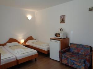a small room with two beds and a chair at Стаи за гости" Герови" in Nesebar