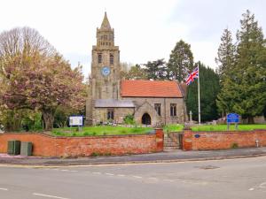 uma velha igreja com uma torre de relógio com uma bandeira em Bunny Lodge - Garden view & free parking em Plumtree