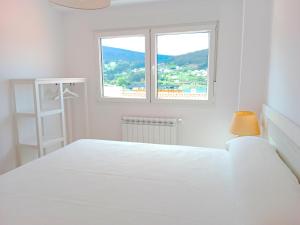 ein weißes Schlafzimmer mit einem Bett und einem Fenster in der Unterkunft Atico en La Ría in Vivero
