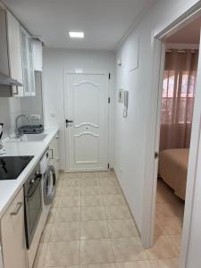 uma cozinha com uma porta branca e uma máquina de lavar e secar roupa em PLAYA SUR (piscina y mar) em Denia