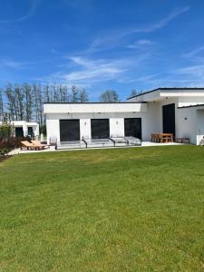 a white building with a lawn in front of it at Golf Villa Stella s bazénom in Šajdíkove Humence