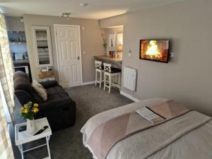 a living room with a couch and a tv on the wall at Bunny Lodge - Garden view & free parking in Plumtree