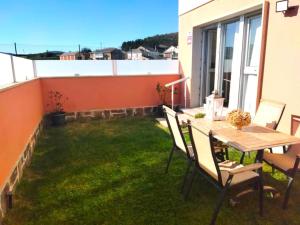patio ze stołem i krzesłami na trawie w obiekcie Apartamento con jardín Playa Foz w mieście Foz