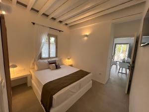 a white bedroom with a bed and a window at Myrto Bungalows in Artemonas