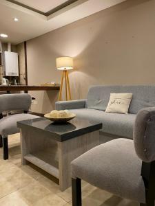 een woonkamer met een bank en een tafel en stoelen bij Aparts Calafate Suites in El Calafate