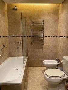 een badkamer met een toilet, een bad en een wastafel bij Aparts Calafate Suites in El Calafate