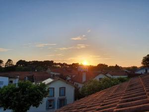 a sunset over a town with houses and roofs at Appartement sur Terrasse in Capbreton +2 photos