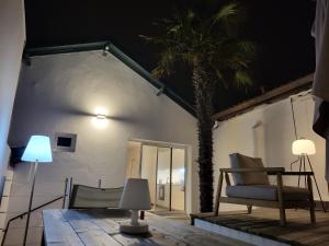 a room with a palm tree and a chair and lamp at Appartement sur Terrasse in Capbreton