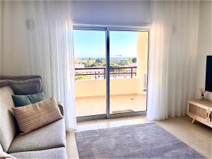 uma sala de estar com um sofá e uma porta de vidro deslizante em Vilamoura Avelãs Ocean View Apartment em Vilamoura