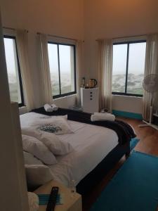 een slaapkamer met een groot bed en grote ramen bij Beachmusic in Kaapstad