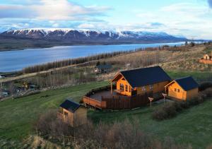 a house on a hill with a lake and mountains at Eys Cabin in Akureyri