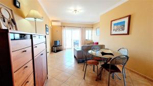 un salon avec une cuisine et une table et des chaises dans l'établissement Quarteira Beach Vacation: 2BR steps to the sand, à Quarteira