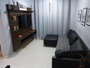 ein Wohnzimmer mit einem schwarzen Sofa und einem TV in der Unterkunft Minha Praia in Rio de Janeiro