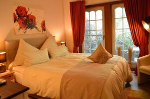 a bedroom with a large white bed with red curtains at Landhaus Zum Heidewanderer in Bad Bevensen