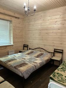 1 Schlafzimmer mit einem Bett, 2 Stühlen und einem Kronleuchter in der Unterkunft Котедж бiля рiчки село Кудашiвка in Kudashevka