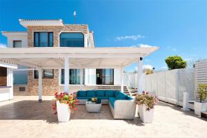 a patio with a blue couch under a pavilion at Cape Serenity Mansion in Ayia Napa