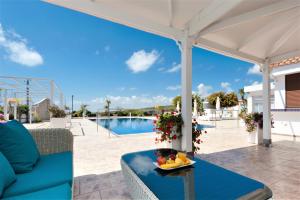 a patio with a blue couch and a table with fruit on it at Cape Serenity Mansion in Ayia Napa