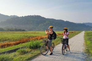 2 personnes en vélo sur un chemin de terre dans l'établissement Cozy AC Shared Bunk Beds in Bayan Lepas, à Bayan Lepas