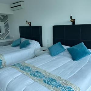 2 camas con almohadas azules juntas en Suite Brisas Cancun, en Cancún