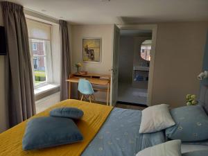 een slaapkamer met een bed met blauwe kussens en een bureau bij B&B Huize Placida in Boxmeer