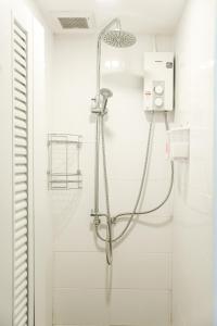 een douche in een badkamer met witte tegels bij Jeune Hostel Chiang Mai - Chang Phuak in Chiang Mai