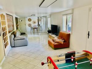 een woonkamer met meubilair en een televisie bij Appartement 120m2 dans maison avec piscine in Boissy-lʼAillerie