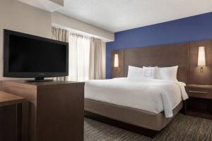 a hotel room with a bed and a flat screen tv at Residence Inn Kansas City Independence in Independence