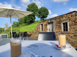 einen Tisch mit einem Getränk und einem Sonnenschirm auf einer Terrasse in der Unterkunft Hostal A Cantina de Renche 