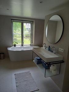 uma casa de banho com uma banheira, um lavatório e um espelho. em B&B Huize Placida em Boxmeer