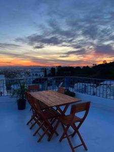 a wooden table and chairs on a balcony with a sunset at The Blue Sea View Sidi Bou Said in Sidi Bou Saïd