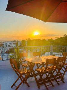 d'une table et de chaises en bois sur un balcon avec vue sur le coucher du soleil. dans l'établissement The Blue Sea View Sidi Bou Said, à Sidi Bou Saïd